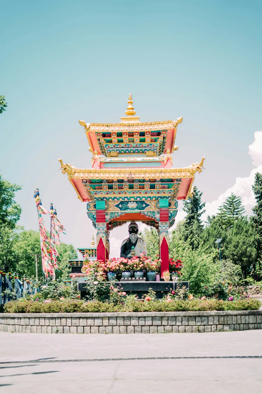 A golden stupa shrine framed by roses in the Tibetan colony at Bir