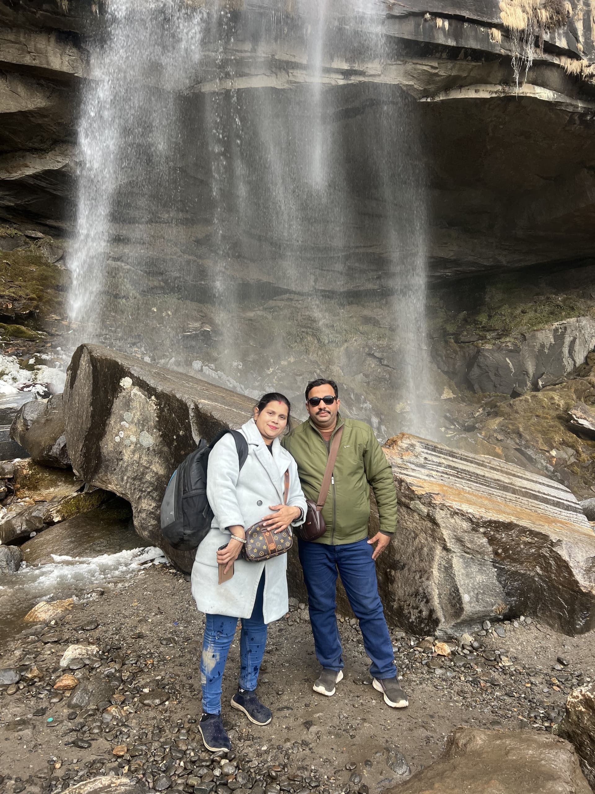 A couple enjoying a Himalayan waterfall on a TripoMusafir trip