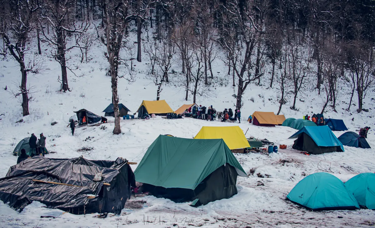 Colourful tents pitched in the snow at the Kedarkantha base camp