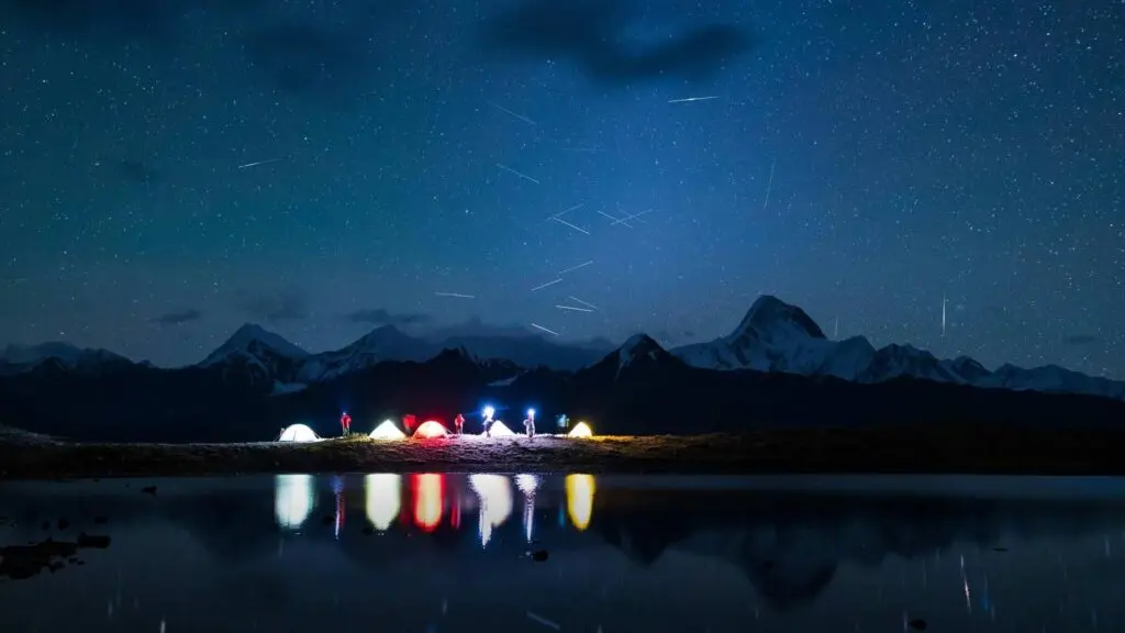 Tents lit up under a starry sky beside Chandratal Lake in Spiti