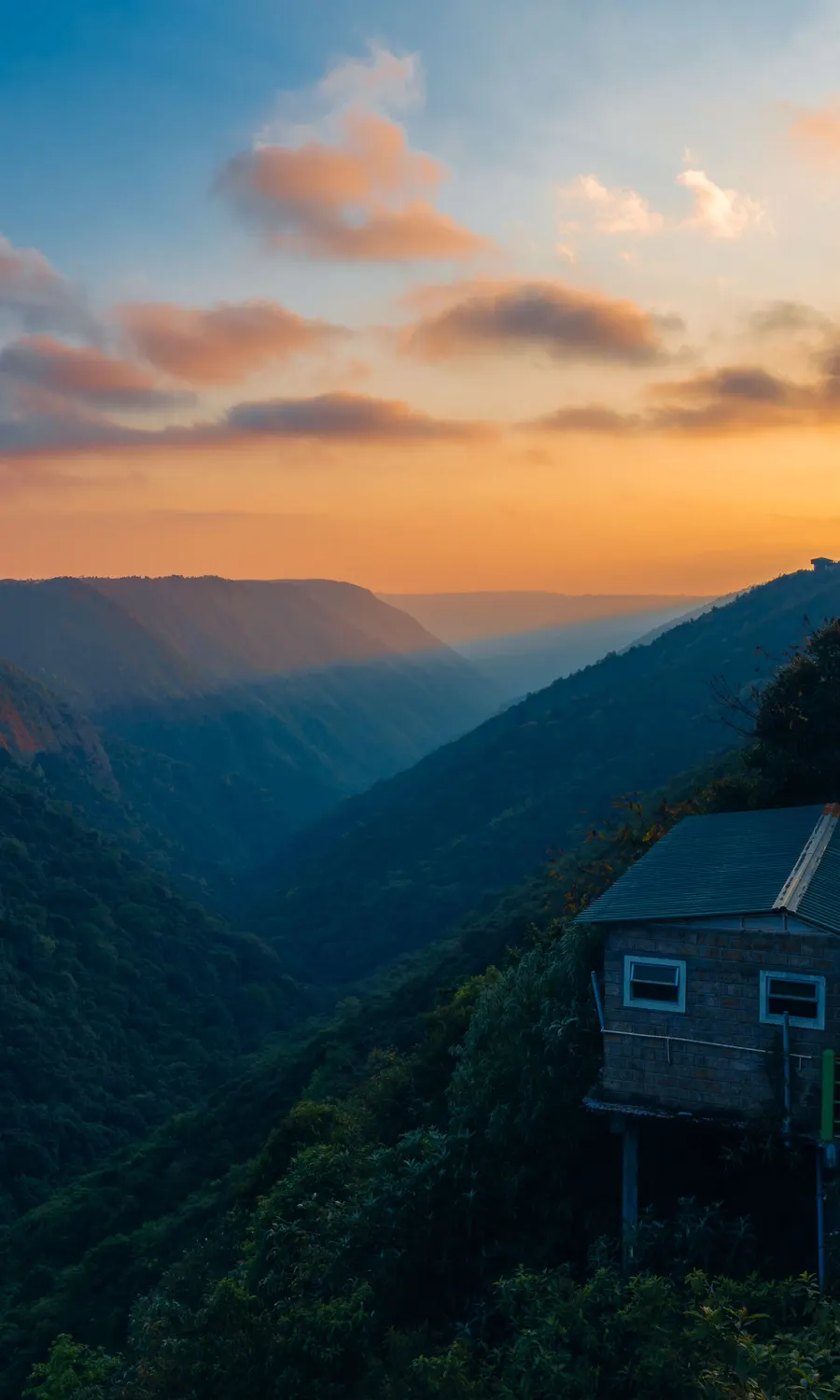 Sunset over the Khasi Hills with a stilted house perched on the cliffside