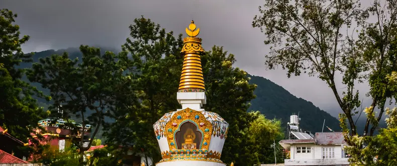 A golden Tibetan stupa in Bir against a dramatic sky