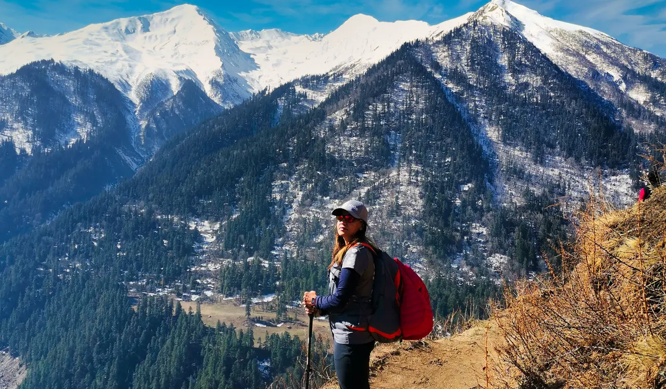Trekker pausing on the ridge trail with the Himalayan range behind