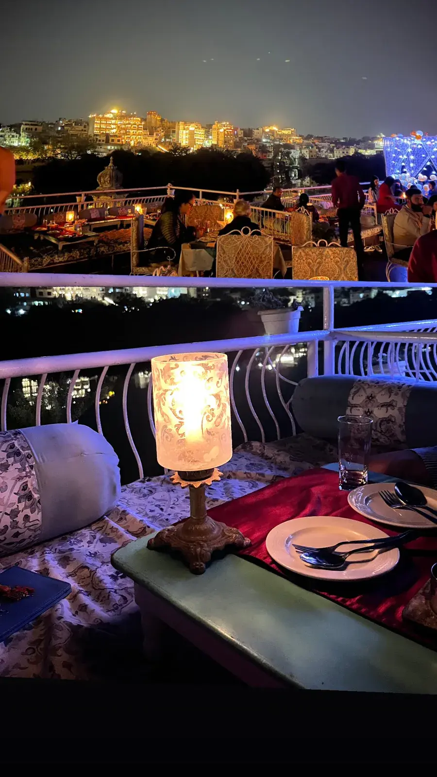 A candlelit rooftop dinner at Ambrai with the illuminated City Palace glowing across Lake Pichola at night